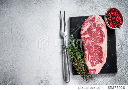 Raw striploin or new york strip steak on a marble board. White background. Top view. Copy space 85877928