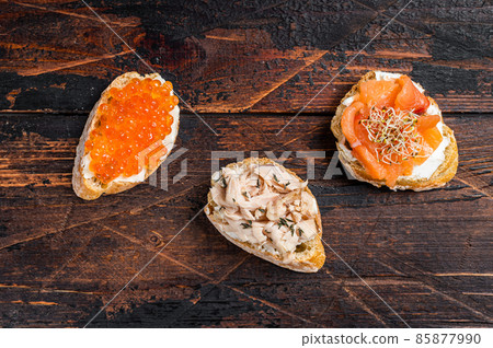 Bruschetta with Hot Smoked salmon, red caviar and herbs. Wooden background. Top view Bruschetta with Hot Smoked salmon, red caviar and herbs. Wooden background. Top view 85877990