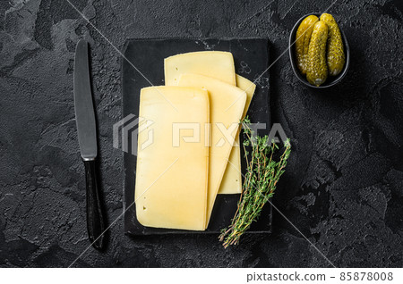 Fresh Uncooked Raclette Swiss cheese slices on marble board. Black background. Top view Fresh Uncooked Raclette Swiss cheese slices on marble board. Black background. Top view 85878008