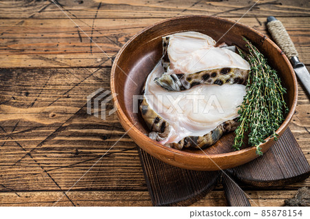Raw wolffish or wolf fish fillet in a wooden plate. wooden background. Top view. Copy space Raw wolffish or wolf fish fillet in a wooden plate. wooden background. Top view. Copy space 85878154