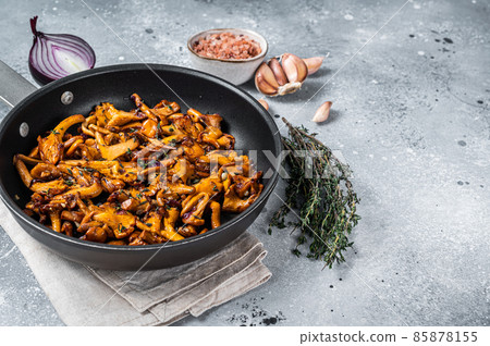 Fried chanterelle mushrooms with onions and thyme in a skillet. Gray background. Top view. Copy space 85878155