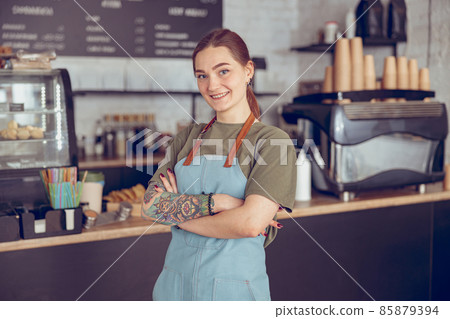 Cheerful female barista in apron standing in coffeehouse 85879394
