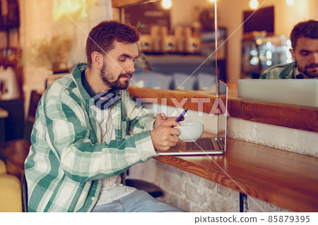 Bearded man using laptop and cellphone in cafe 85879395