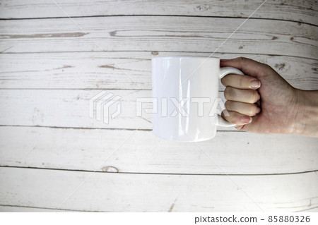 Hand holding a ceramic mug blank on wooden background with copy space, Hand holding a ceramic mug blank on wooden background with copy space, 85880326