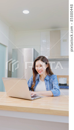woman uses laptop at kitchen woman uses laptop at kitchen 85880448