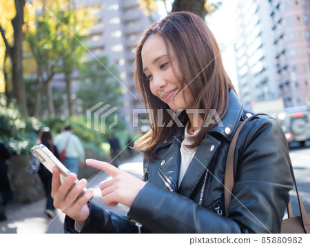 [Urban] A woman operating a smartphone in the town 85880982