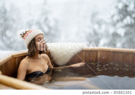 Woman relaxing in hot bath at snowy mountains Woman relaxing in hot bath at snowy mountains 85881101