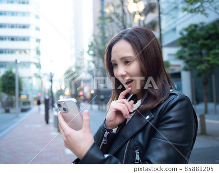 [Urban] A woman operating a smartphone in the town 85881205