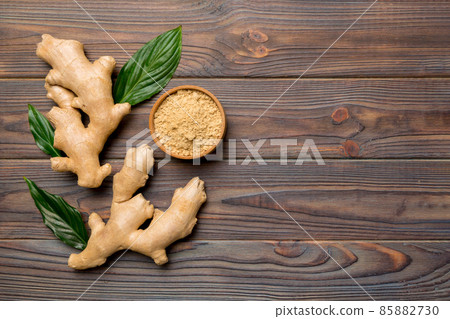 Finely dry Ginger powder in bowl with green leaves isolated on colored background. top view flat lay 85882730