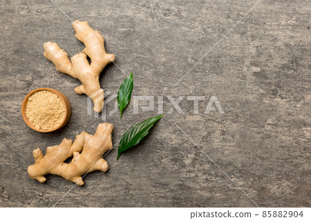 Finely dry Ginger powder in bowl with green leaves isolated on colored background. top view flat lay Finely dry Ginger powder in bowl with green leaves isolated on colored background. top view flat lay 85882904