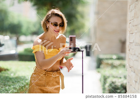 A beautiful girl records her daily blog video on a smartphone mounted on a tripod 85884158
