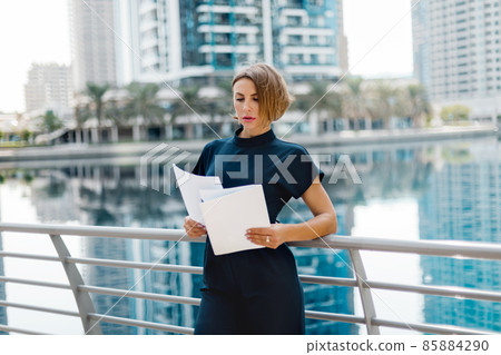 A business woman looks through documents during a break on the street 85884290