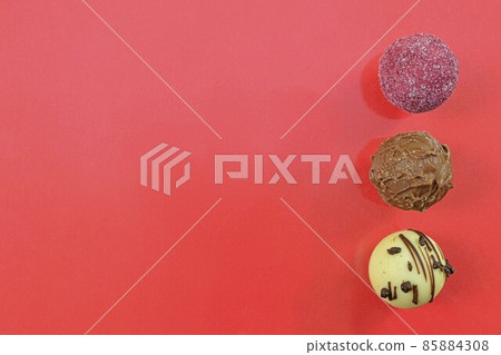 Collection of chocolate sweets on a colorful background. Chocolate pralines on a red background with copy space. Flat lay, top view Collection of chocolate sweets on a colorful background. Chocolate pralines on a red background with copy space. Flat lay, top view 85884308
