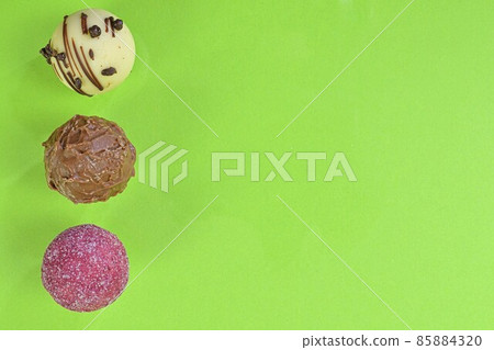 Chocolate bonbons or pralines on green background. Assortment of chocolate pralines on light green background with copy space. Flat lay, top view Chocolate bonbons or pralines on green background. Assortment of chocolate pralines on light green background with copy space. Flat lay, top view 85884320
