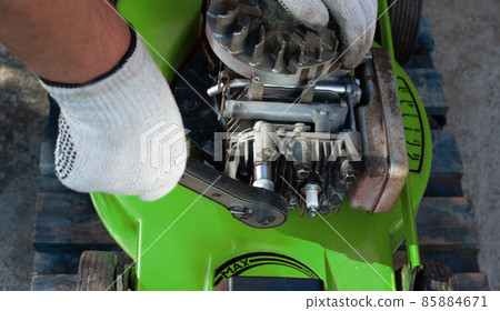 Man repairing an old lawn mower, gas engine. 85884671