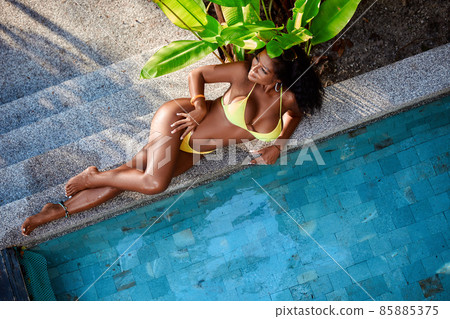 Young asian girl in yellow bikini posing near swimming pool Young asian girl in yellow bikini posing near swimming pool 85885375