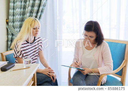 Woman teacher, therapist, social worker talking to teenage student in the office. 85886175