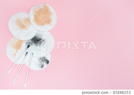 Used cotton pads and cotton swabs. Used cosmetic pad after removing make-up. Pink background. Place for text. Copy space. Flat lay. Dirty 85886253