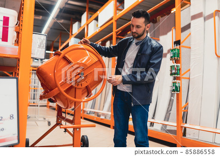 a man in a hardware store inspecting a concrete mixer a man in a hardware store inspecting a concrete mixer 85886558