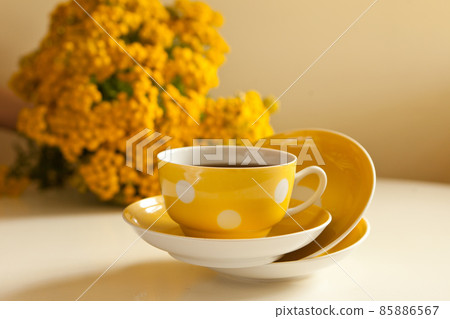 yellow cup levitation with black tea. retro tea-set with flowers. vintage mug and plates on the table yellow cup levitation with black tea. retro tea-set with flowers. vintage mug and plates on the table 85886567