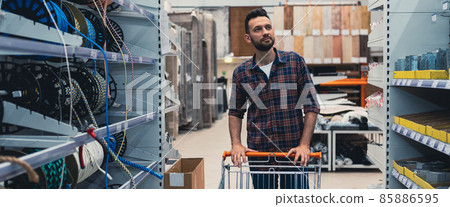 a buyer in a hardware store walks between the aisles with goods with a trolley a buyer in a hardware store walks between the aisles with goods with a trolley 85886595