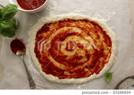 Pizza coooking process with sourdough homemade natural east dough, top view, tomatoes sauce and basil Pizza coooking process with sourdough homemade natural east dough, top view, tomatoes sauce and basil 85886694