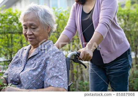 Caregiver help Asian senior or elderly old lady woman on wheelchair in park. 85887008