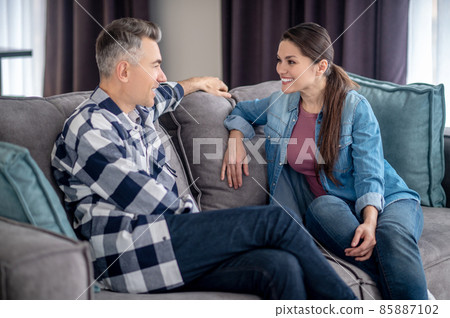 Man and woman sitting on couch looking at each other 85887102