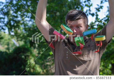 Surprised Adult man holds children's ships tied to a branch 85887333