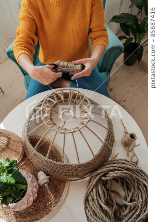 Woman makes handmade diy lamp from jute rope Woman makes handmade diy lamp from jute rope 85887416