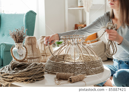 Woman makes handmade diy lamp from jute rope Woman makes handmade diy lamp from jute rope 85887421