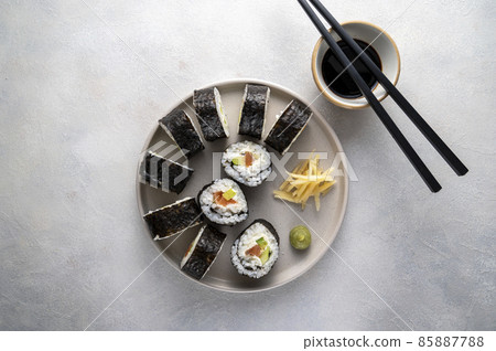 Sushi on round plate with chopsticks, soy sauce. ginger. Homemade rolls with salmon, avocado and cucumber. Sushi on round plate with chopsticks, soy sauce. ginger. Homemade rolls with salmon, avocado and cucumber. 85887788