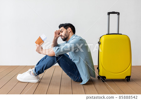 Upset arab man with passport and plane tickets leaning on suitcase, missed his vacation because of COVID-19 pandemic Upset arab man with passport and plane tickets leaning on suitcase, missed his vacation because of COVID-19 pandemic 85888542