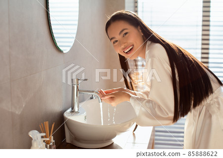 Happy long-haired chinese woman washing her face 85888622