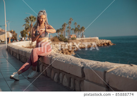 Adult woman resting after training by the waterfront Adult woman resting after training by the waterfront 85888774
