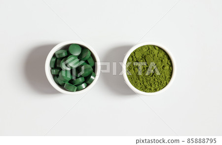 Chlorella and spirulina. Spirulina pills and chlorella green powder on a white background. Mineral food additive. Top view, flat lay. Chlorella and spirulina. Spirulina pills and chlorella green powder on a white background. Mineral food additive. Top view, flat lay. 85888795
