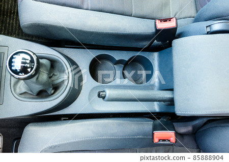 Mechanical gear lever close up. A car with a six speed transmission. Handbrake and seat belt fasteners. Mechanical gear lever close up. A car with a six speed transmission. Handbrake and seat belt fasteners. 85888904