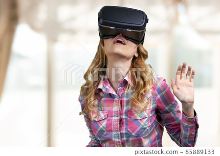 Excited young woman using virtual reality glasses. Excited young woman using virtual reality glasses. 85889133