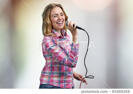 Young beautiful woman performing song on abstract bokeh background. 85889268