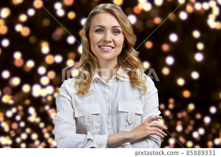 Pretty smiling woman in white blouse looking at camera with crossed arms. 85889331