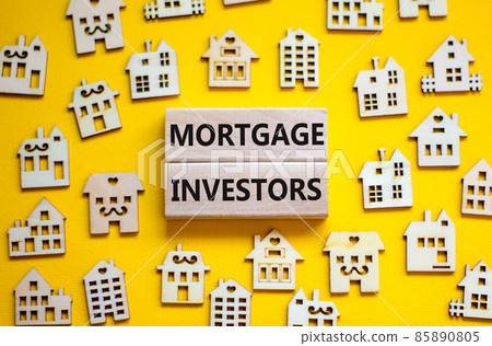 Mortgage investors symbol. Concept words 'Mortgage investors' on wooden blocks near miniature wooden houses. Beautiful yellow background. Business, mortgage investors concept. 85890805