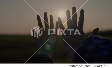 hands at sunset, lovers reach for the sky, dream of a good, good desire of people, ask for help from the sun, pray in the rays of sunlight, bright glare through the fingers of people's palms 85891388