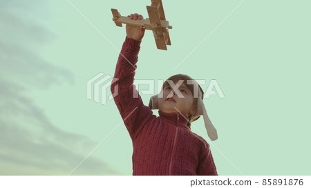 little child in a helmet plays with an airplane against sky, childhood dream to fly, kid wants to become an airplane pilot, imagination, happy family, cheerful baby makes illusion flight in fantasies little child in a helmet plays with an airplane against sky, childhood dream to fly, kid wants to become an airplane pilot, imagination, happy family, cheerful baby makes illusion flight in fantasies 85891876