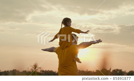 child sits on her father shoulders dreaming of flying at sunset, girl glare of the sun wants to be pilot, play with dad together, baby plays with her parent in nature in wings, happy family, travel child sits on her father shoulders dreaming of flying at sunset, girl glare of the sun wants to be pilot, play with dad together, baby plays with her parent in nature in wings, happy family, travel 85891877