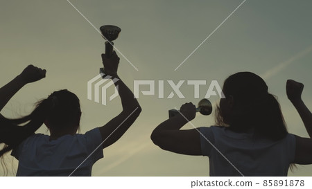 silhouette of a girl with cup in hand rejoice in victory, jump up with happiness, achieve success by earning gold, active competition and receiving trophy, laugh and hug in teamwork, smiles in sports silhouette of a girl with cup in hand rejoice in victory, jump up with happiness, achieve success by earning gold, active competition and receiving trophy, laugh and hug in teamwork, smiles in sports 85891878