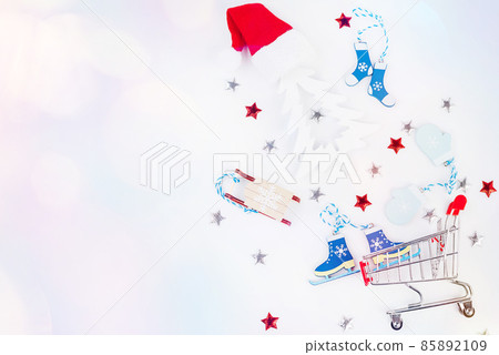 Trolley from a supermarket with New Year's gifts and New Year's toys on a light background.Flat lay, top view, wide banner.Christmas and New Year background. Trolley from a supermarket with New Year's gifts and New Year's toys on a light background.Flat lay, top view, wide banner.Christmas and New Year background. 85892109