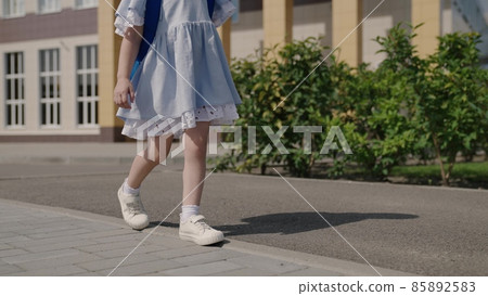 Happy little girl playing in the schoolyard, a little kid with a backpack, a child's school bag on the baby's shoulders, a fun child's primary education, a childhood dream, a fun school life 85892583