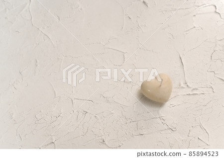 handmade candle in the shape of a heart. on a white textured background 85894523