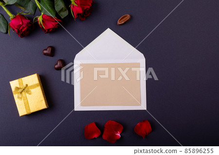Overhead view of blank letter and gift box by red roses on table, copy space Overhead view of blank letter and gift box by red roses on table, copy space 85896255