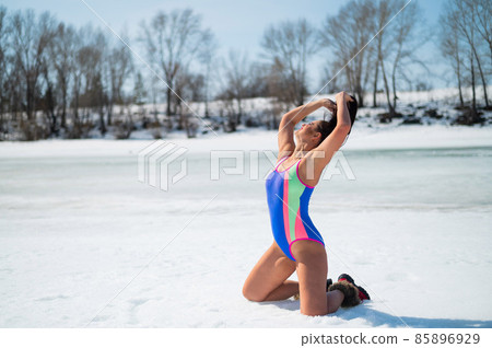Caucasian woman in a swimsuit sunbathes on the snow in winter. 85896929